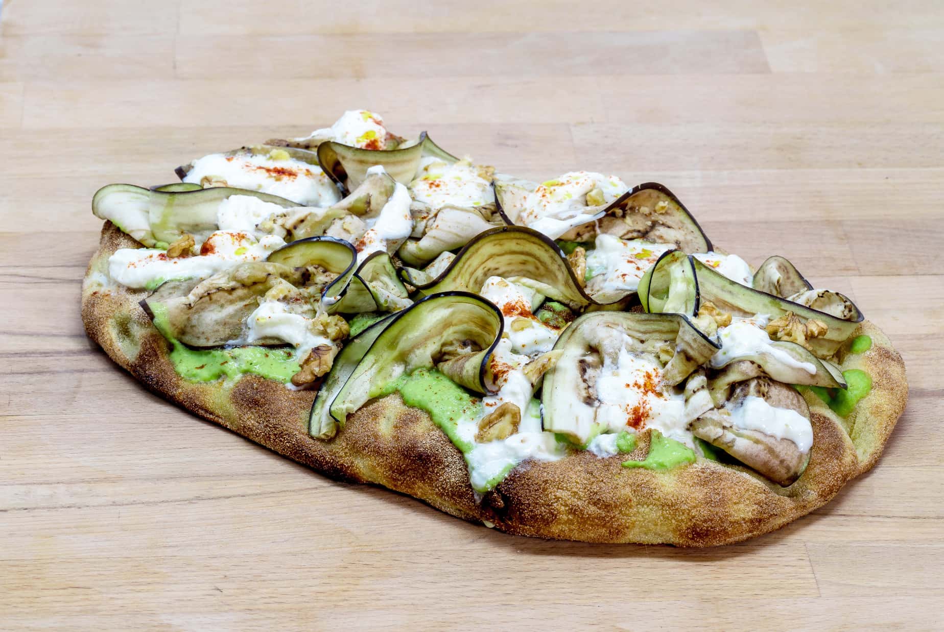 Photo of a Pinsa topped with zucchini, burrata cheese and sauces
